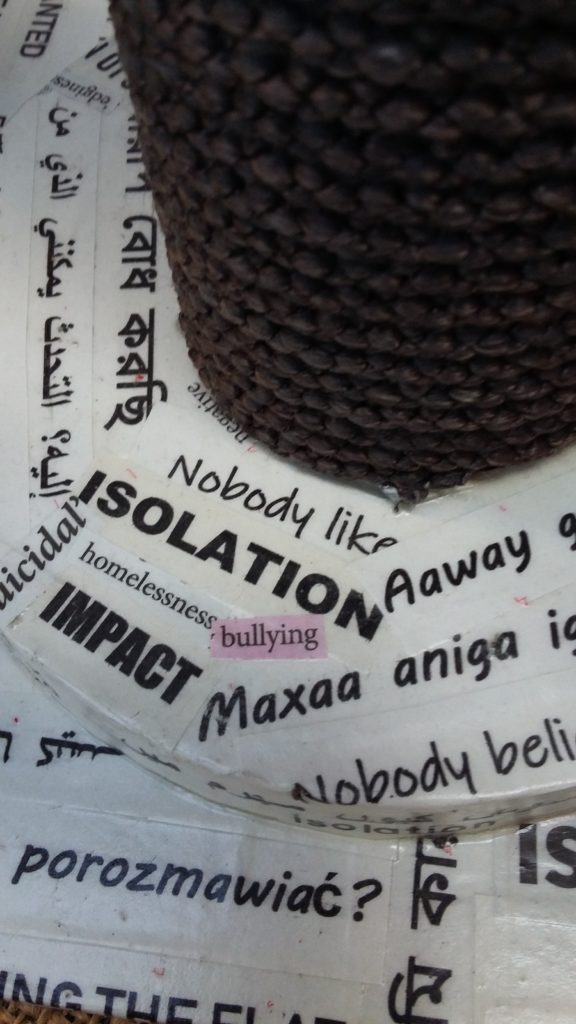 Base of the craftwork,
showing phrases in different languages, including: 'Isolation', 'bullying',
'impact', 'Suicidal'